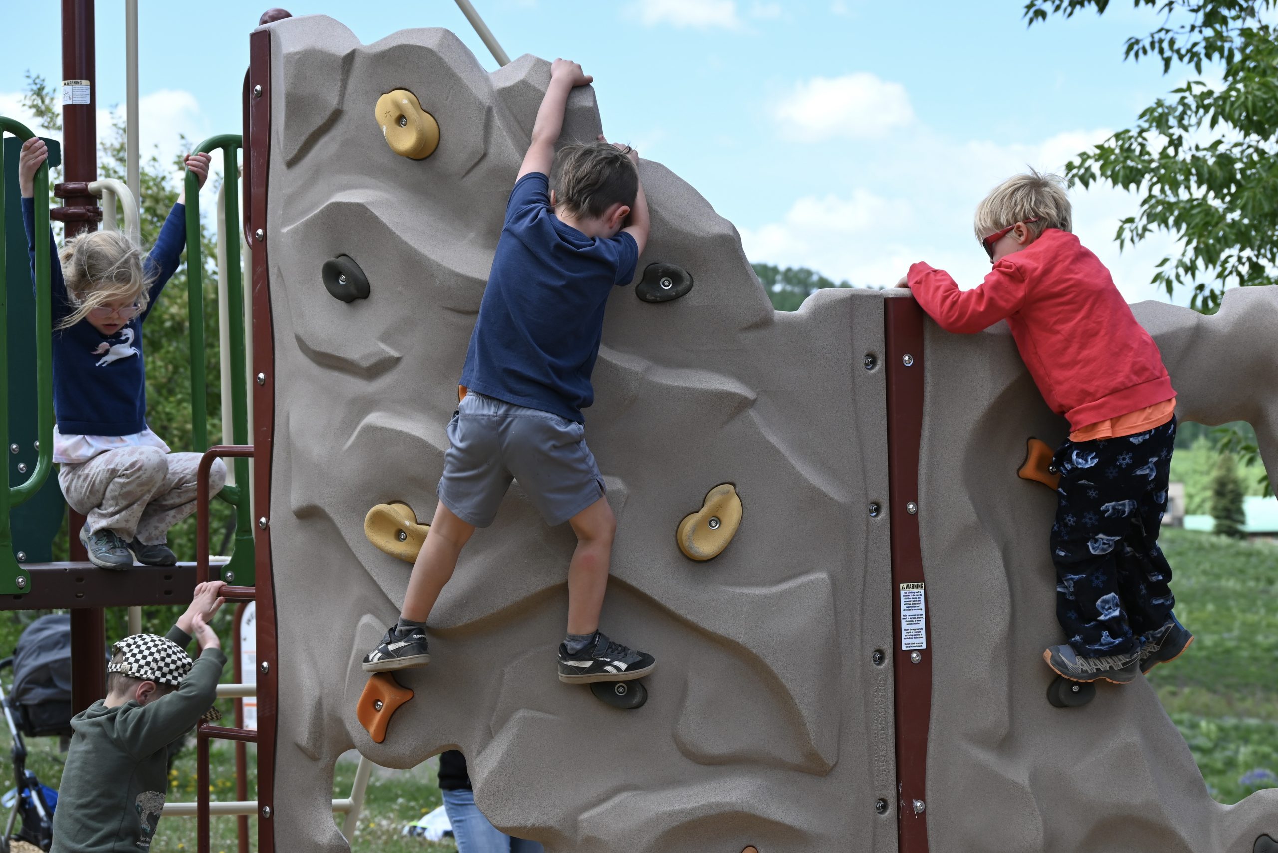 Children clamber along the playground's mini rock wall.